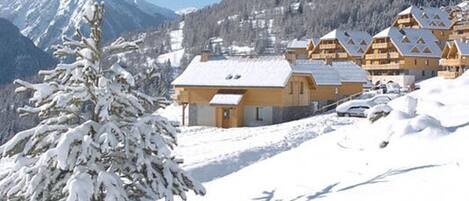A snow-covered mountain with a row of wooden chalets.