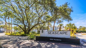 A sign for Seascape at 9002 Palmetto with a paved walkway and trees in the background.