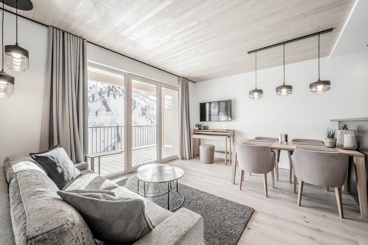 Een moderne woonkamer met een bank, salontafel en een eethoek met stoelen.