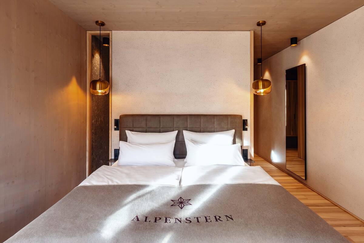 A hotel room with a bed, a headboard, and two pendant lights.