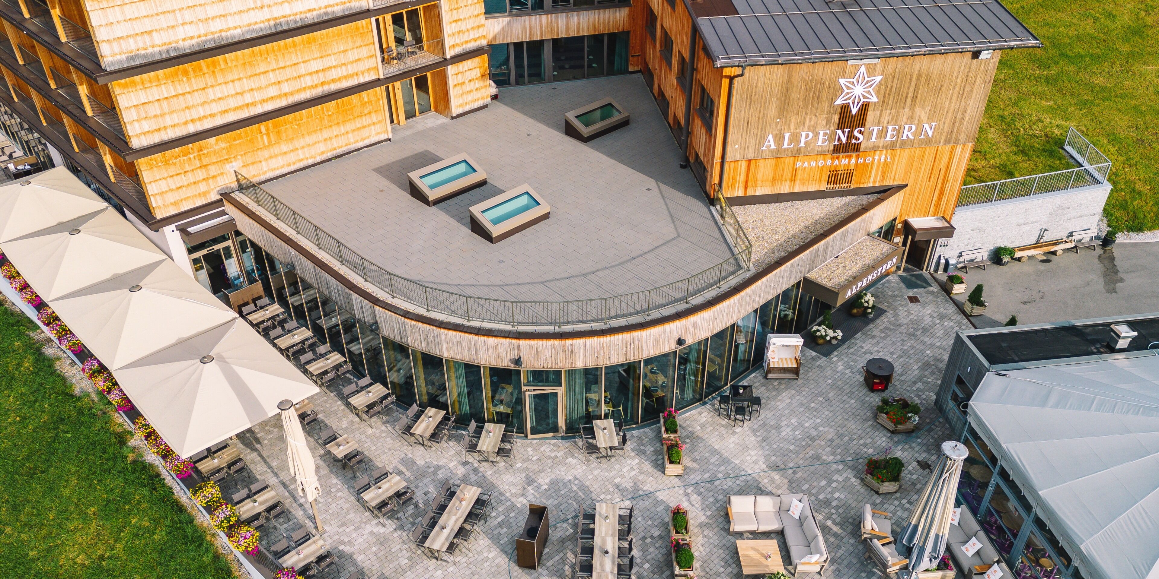 A modern hotel with a curved roof, outdoor seating, and a wooden facade.
