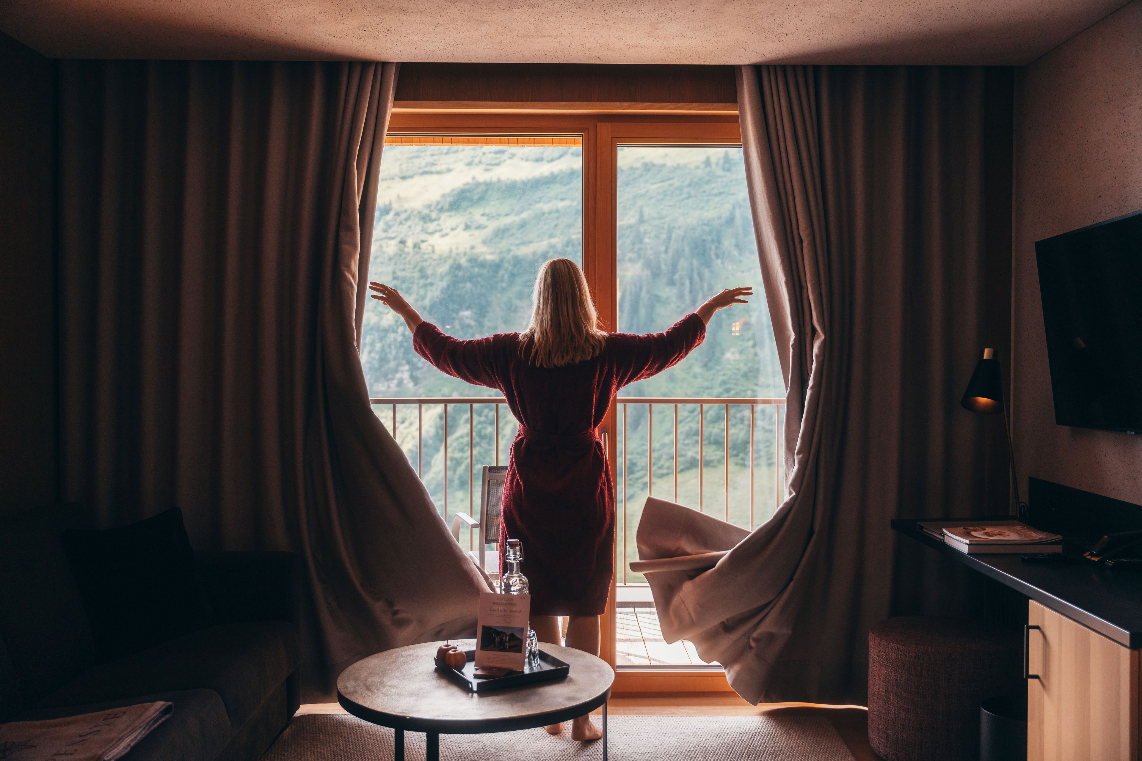 Ein Zimmer mit einem großen Fenster, einem Tisch mit Tablett und einem Fernseher.