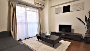 A modern living room with a sofa, a coffee table, a TV, and a plant.