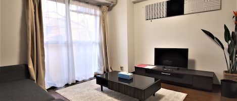 A modern living room with a sofa, a coffee table, a TV, and a plant.