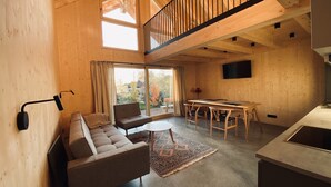 A modern interior with a loft-style ceiling, a sofa, a dining table, and a kitchen area.