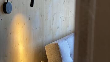 Ein modernes Zimmer mit einer Holzwand, einer Couch und einer wandmontierten Leuchte.