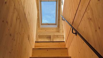 A wooden staircase with a skylight at the top.