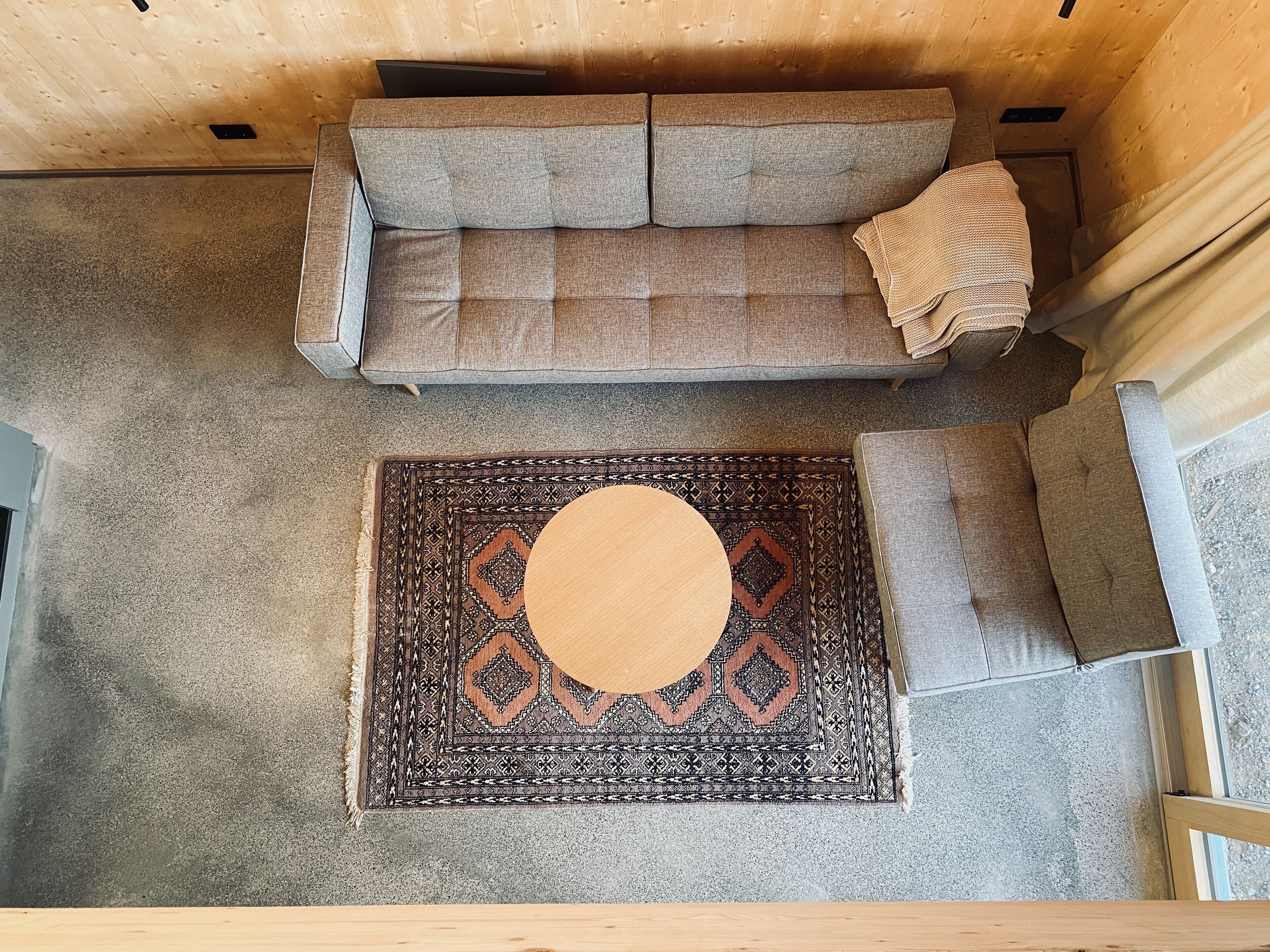 Ein gemütliches Zimmer mit einer Couch, einem Teppich mit Muster und einem kleinen Holztisch.