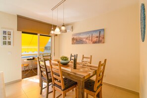 A dining area with a wooden table, chairs, a plant, and a painting on the wall.