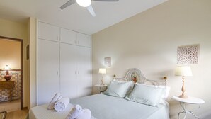 Un dormitorio con cama, dos mesitas de noche, ventilador de techo y armario.