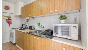 Una cocina con armarios de madera, microondas, pileta y estufa.