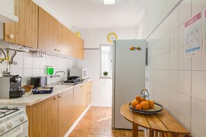A kitchen with wooden cabinets, a stove, a microwave, and a refrigerator.