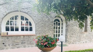 Un bâtiment en pierre doté de fenêtres en arc de cercle et d’un pot de fleurs posé sur le sol.