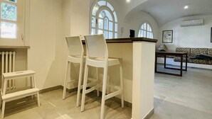 Une cuisine spacieuse avec un haut plafond, des tabourets de bar blancs et un îlot central.