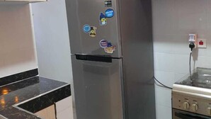 Keittiössä on ruostumattomasta teräksestä valmistettu jääkaappi, musta marmoritaso, liesi ja puiset kaapit.