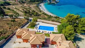 Un complexe hôtelier doté d’une piscine, de bâtiments aux toits de tuiles et offrant une vue sur la plage.