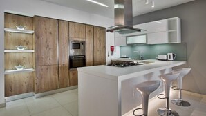 Een moderne keuken met houten kastjes, een centraal eiland, barkrukken en roestvrijstalen apparatuur.