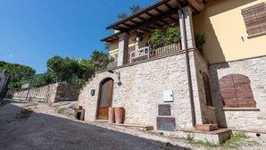 Un edificio de piedra con balcón, una puerta de madera y un pequeño jardín.