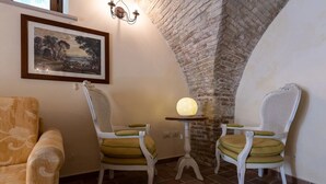 Una habitación acogedora con pared de ladrillo rústica, un cuadro de paisaje enmarcado y dos sillones de mimbre con cojines.