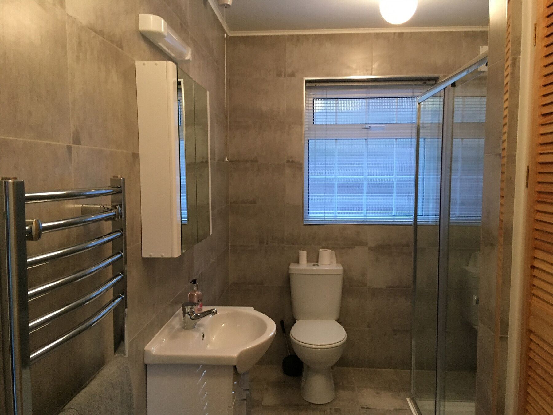 A bathroom with a glass shower enclosure, a white sink, and a toilet.