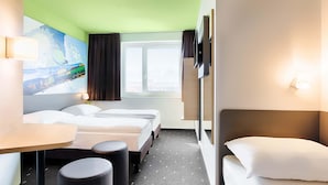 Habitación de hotel con dos camas, un escritorio y un cuadro en la pared.