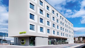 Un hotel moderno con una zona de recepción, varios pisos y cielo despejado.