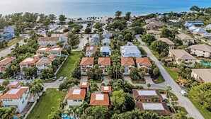 Vista aérea de uma área residencial à beira-mar, com casas, ruas e uma praia.