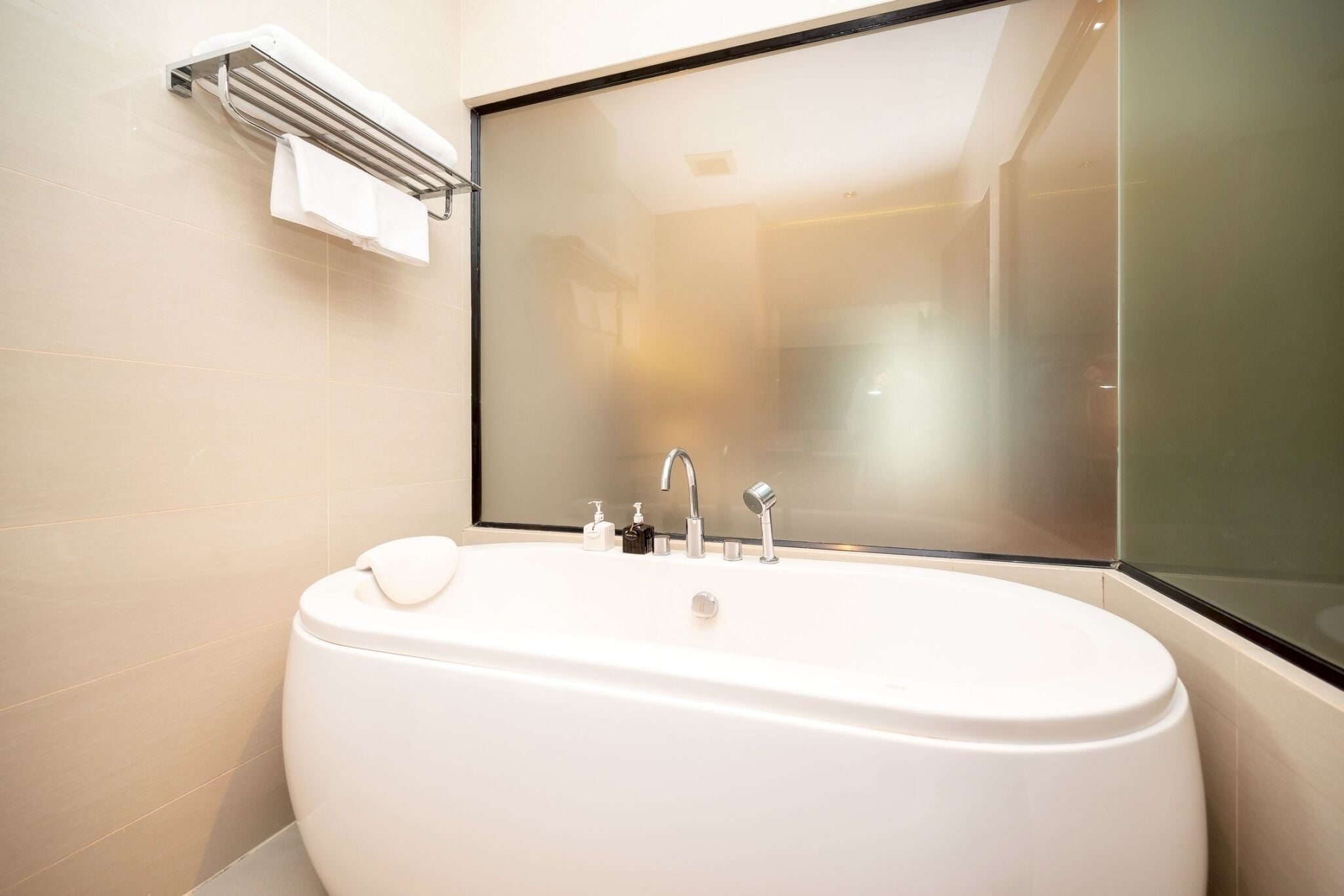 A modern bathroom with a freestanding bathtub, a mirror, and a towel rack.