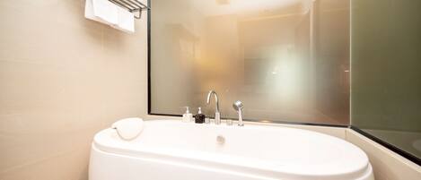 A modern bathroom with a freestanding bathtub, a mirror, and a towel rack.