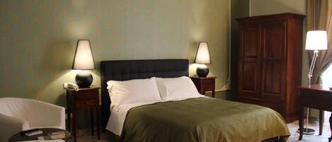 A hotel room with a bed, two bedside tables with lamps, a wooden wardrobe, and a chair.