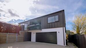 Ein modernes, zweistöckiges Haus mit Garage, Balkon und einem großen Fenster.
