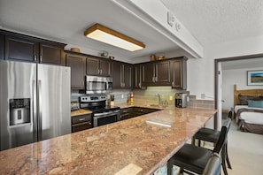A modern kitchen with dark wood cabinets, stainless steel appliances, and a granite countertop.