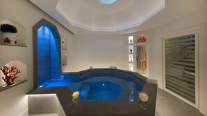 Um spa moderno com banheira de hidromassagem, claraboia e teto com design geométrico.