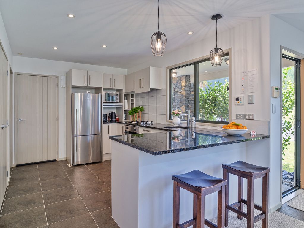 A modern kitchen with a large island, stainless steel appliances, and pendant lighting.