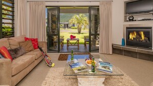 A living room with a sofa, coffee table, and fireplace. - Villa 51 - Pauanui Holiday Home (Pauanui)