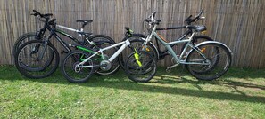 Trois vélos sont garés contre une clôture en bois.