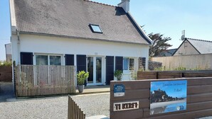 Un bâtiment blanc avec un toit en pente, une clôture en bois et une enseigne indiquant qu’il s’agit d’un lieu estival.