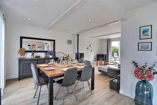 A modern living space with a dining area, kitchen, and a seating area with a view.