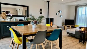 Un salon moderne avec une table à manger en bois, des chaises colorées, un canapé, un téléviseur et une cheminée.