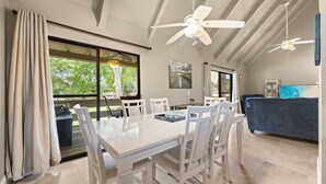 A dining area with a white table and chairs, a ceiling fan, and large windows with curtains. - Seascape Resort Villa - Our Happy Place (Miramar Beach)