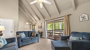 A spacious living room with a ceiling fan, a sliding glass door to a patio, and a 'This is our happy place' sign. - Seascape Resort Villa - Our Happy Place (Miramar Beach)