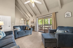 A spacious living room with a ceiling fan, a sliding glass door to a patio, and a 'This is our happy place' sign.