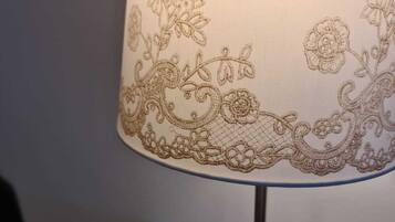 En bordlampe med en dekorativ stofskærm med blomster- og paisley-mønstre.