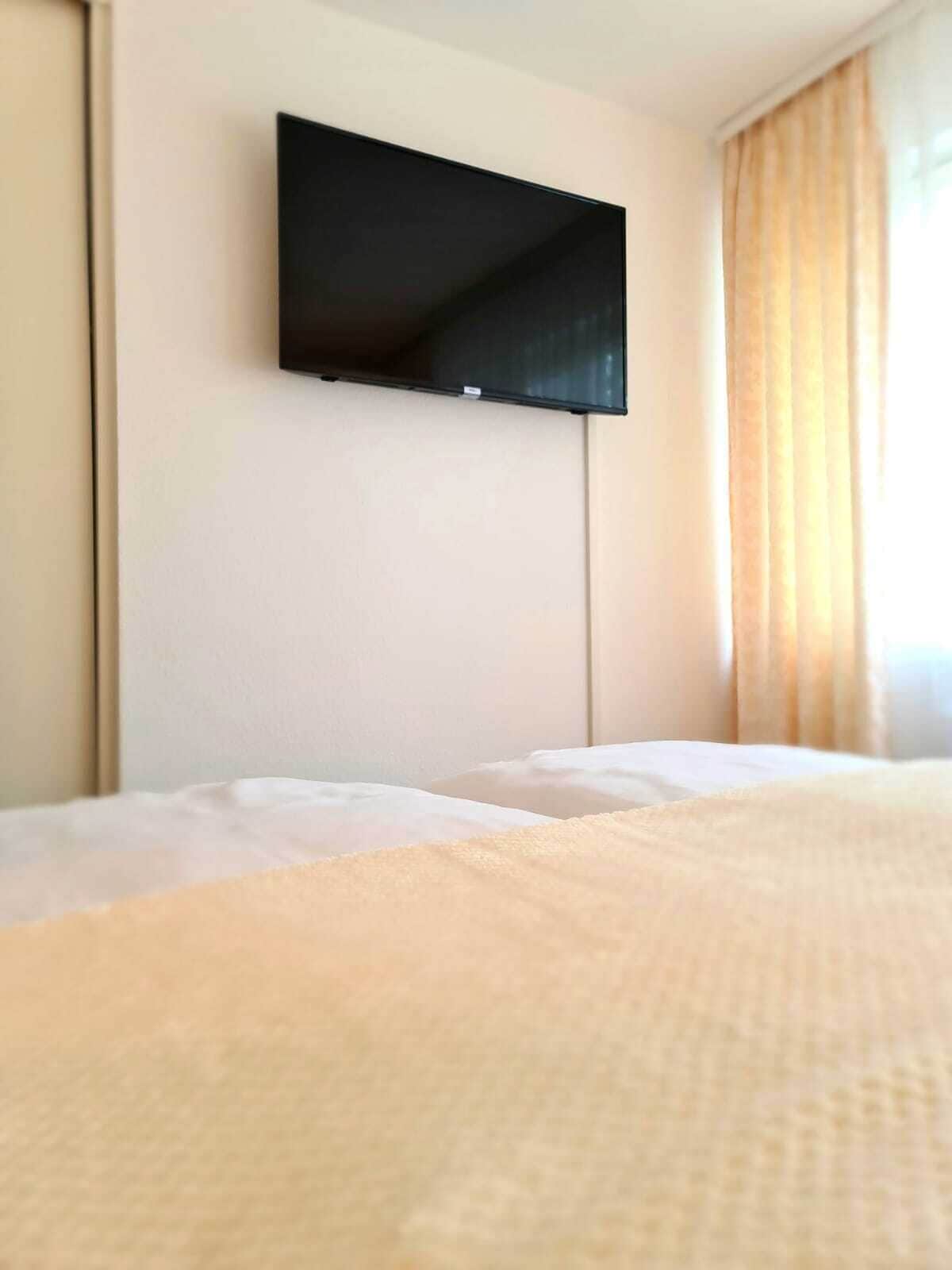 Een hotelkamer met een bed, een flatscreen televisie aan de muur en een raam met gordijnen.
