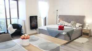 Un dormitorio moderno con cama, mesita de noche, lámpara y una zona de comedor con mesa y sillas.