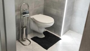 Un baño moderno con inodoro, ducha y perchero para toallas.