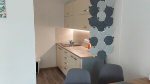 Una cocina compacta con encimera de madera, un fregadero y armarios. Hay una zona de comedor con una mesa y sillas.