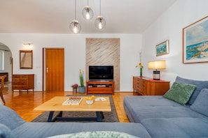 Relax in this stylish living room with a large flat-screen TV, comfortable sofa, and wooden coffee table.