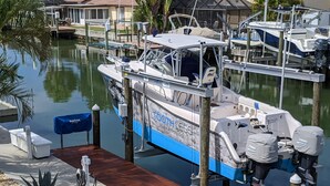 A boat docked at a marina with a wooden dock, a covered seating area, and a small table.