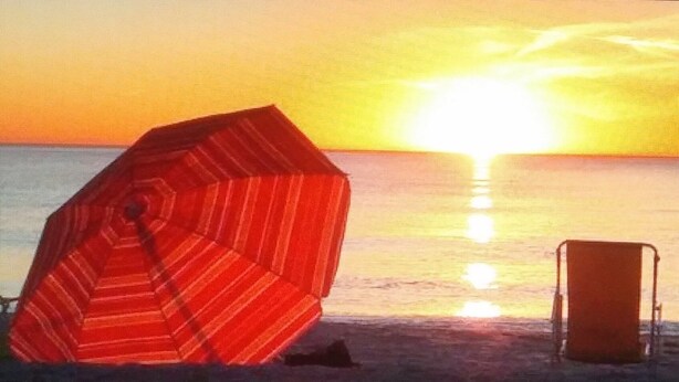 A beach scene with a striped umbrella and a beach chair.